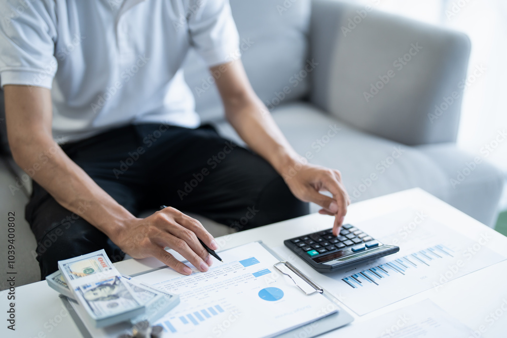 Saving money. Man calculate finances home pay bills taxes savings economy financial at home and saving money stacking coins with calculator Saving money. Man calculate finances home pay bills taxes savings economy financial at home and saving money stacking coins with calculator
