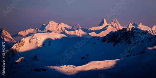 Shadows on the mountains covered by snow at sunrise; mountain peaks covered by snow in winter