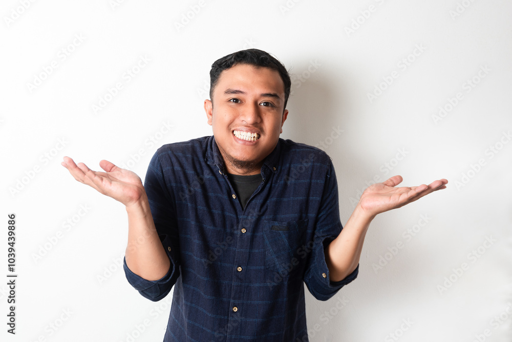 Asian man looking at camera with smiling expression with both hands raised to the side Asian man looking at camera with smiling expression with both hands raised to the side