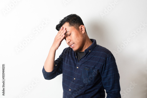 Adult Asian man with head down showing stress expression photo