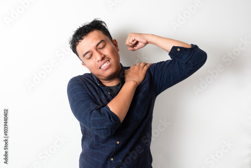 Adult Asian man touching his left shoulder with pain expression