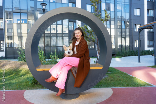 Portrait of two best friends. Smiling girl and her corgi dog puppy enjoy the sunny weather during the walk. Lovely pets.