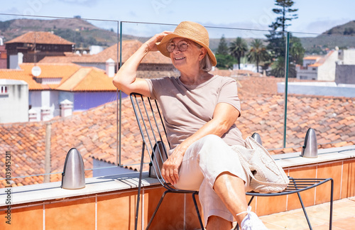 Happy traveler senior woman in vacation visiting La Laguna in Santa Cruz de Tenerife admiring cityscape from the hotel roof