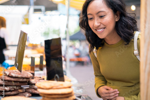 Smiling pregnant woman buying cookies from market photo