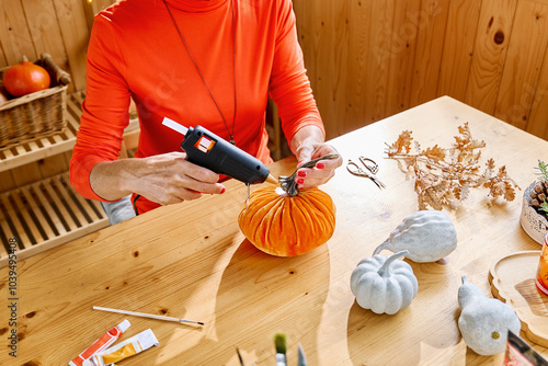 Woman gluing stem on artificial pumpkin at home