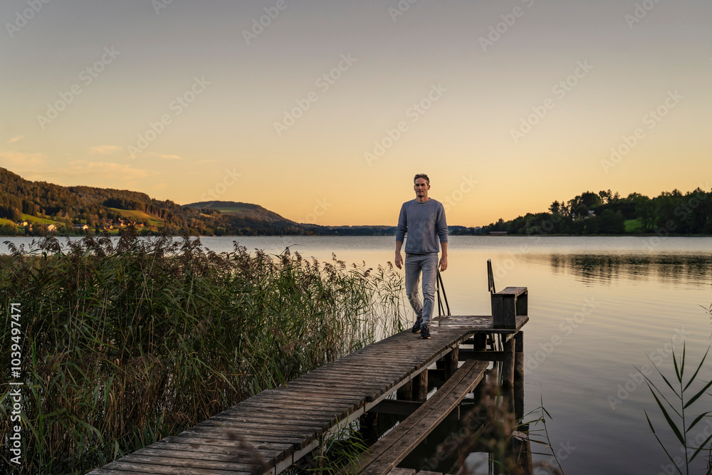 Man walking on jetty near sea at sunrise Man walking on jetty near sea at sunrise