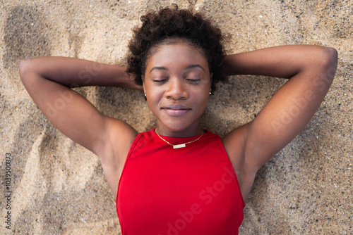 Young woman with hands behind head sleeping on sand at beach photo