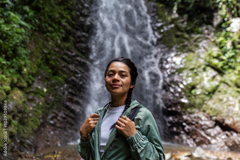 Smiling woman standing in front of waterfall at forest Smiling woman standing in front of waterfall at forest