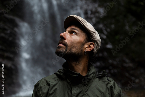 Man wearing cap in front of waterfall photo