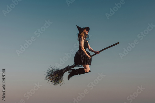Woman wearing witch costume and flying in blue sky at Halloween