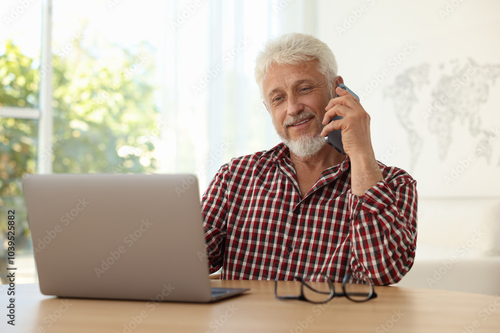Senior man talking on phone at table indoors Senior man talking on phone at table indoors