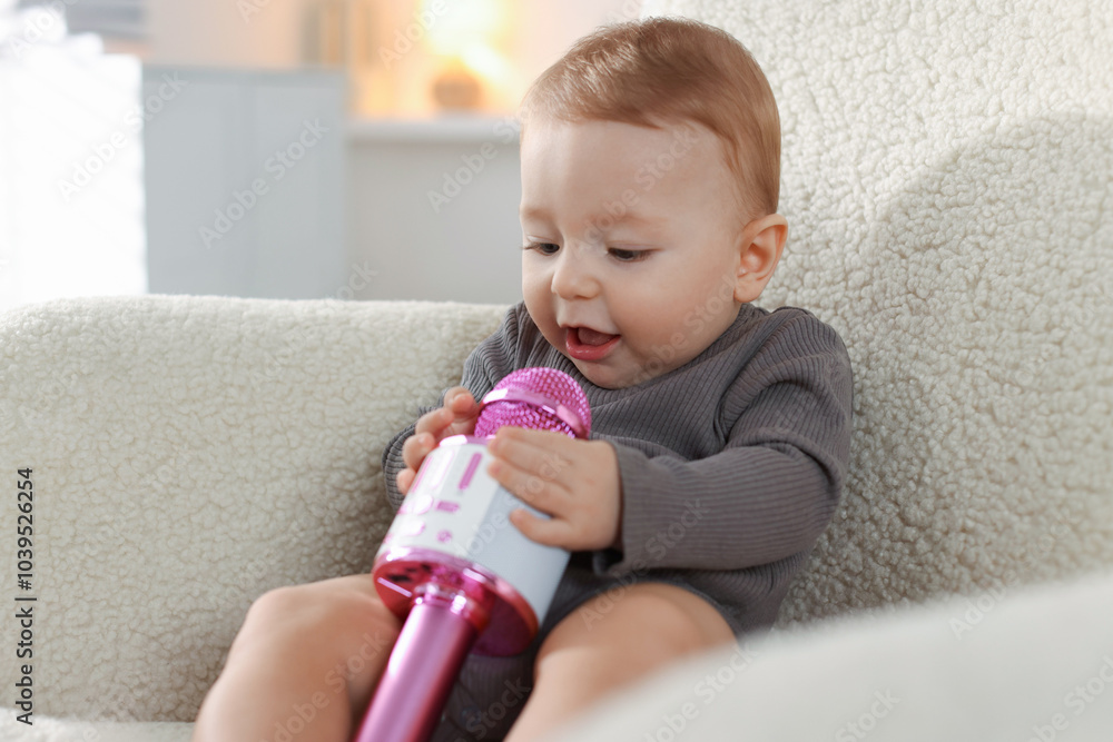 Cute little baby with microphone on armchair at home Cute little baby with microphone on armchair at home