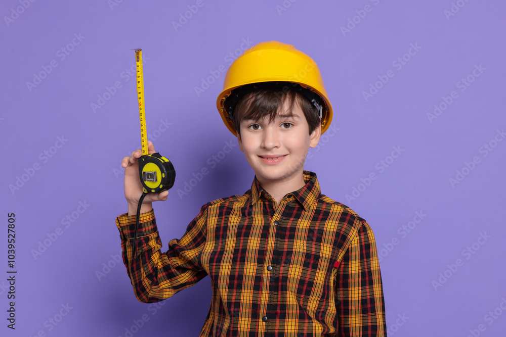 Boy with measuring tape pretending to be builder on violet background. Dreaming of future profession Boy with measuring tape pretending to be builder on violet background. Dreaming of future profession
