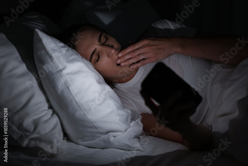 Bad habit. Young woman using smartphone in bed at night