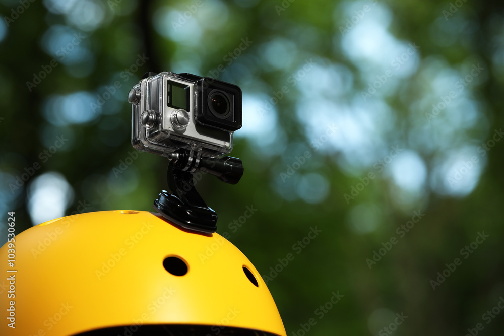 Modern action camera with mount on helmet outdoors, closeup. Space for text Modern action camera with mount on helmet outdoors, closeup. Space for text