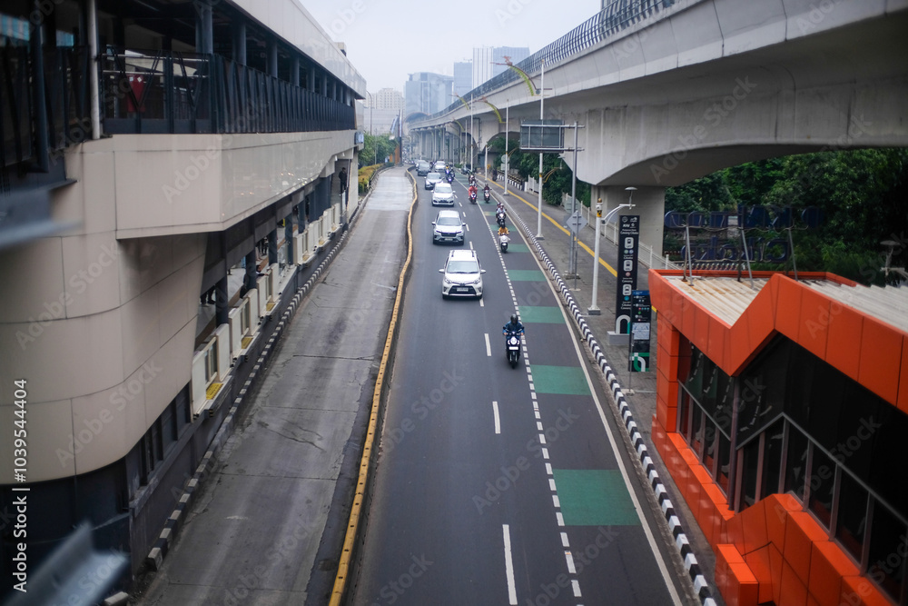 A modern urban road in Jakarta, Indonesia, shows cars and motorbikes traveling beneath an elevated transit system. A modern urban road in Jakarta, Indonesia, shows cars and motorbikes traveling beneath an elevated transit system.