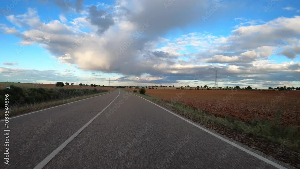 Driving car on empty regional road through the fields outside the city during sunny day in Spain. Countryside asphalt road landscape scene. Traffic ways transportation logistics and traveling concept Driving car on empty regional road through the fields outside the city during sunny day in Spain. Countryside asphalt road landscape scene. Traffic ways transportation logistics and traveling concept