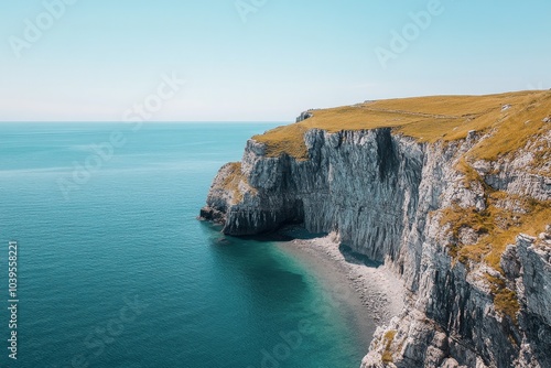 Towering white cliffs contrast beautifully with the deep blue of the sea under a clear sky, creating a breathtaking view of nature's grandeur and majesty.