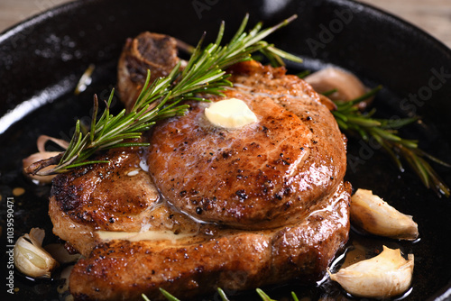 Pork cutlet on the bone in a piece of butter with garlic and rosemary in a frying pan  photo