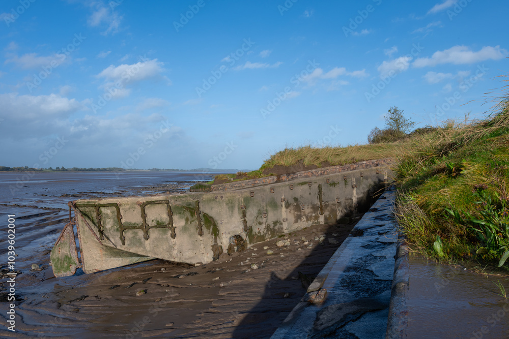 Shipwrecked barges on the side of an estuary covered in grass and mud. Shipwrecked barges on the side of an estuary covered in grass and mud.