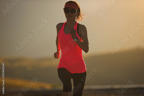 Fitness woman runner running in sunset mountain road photo