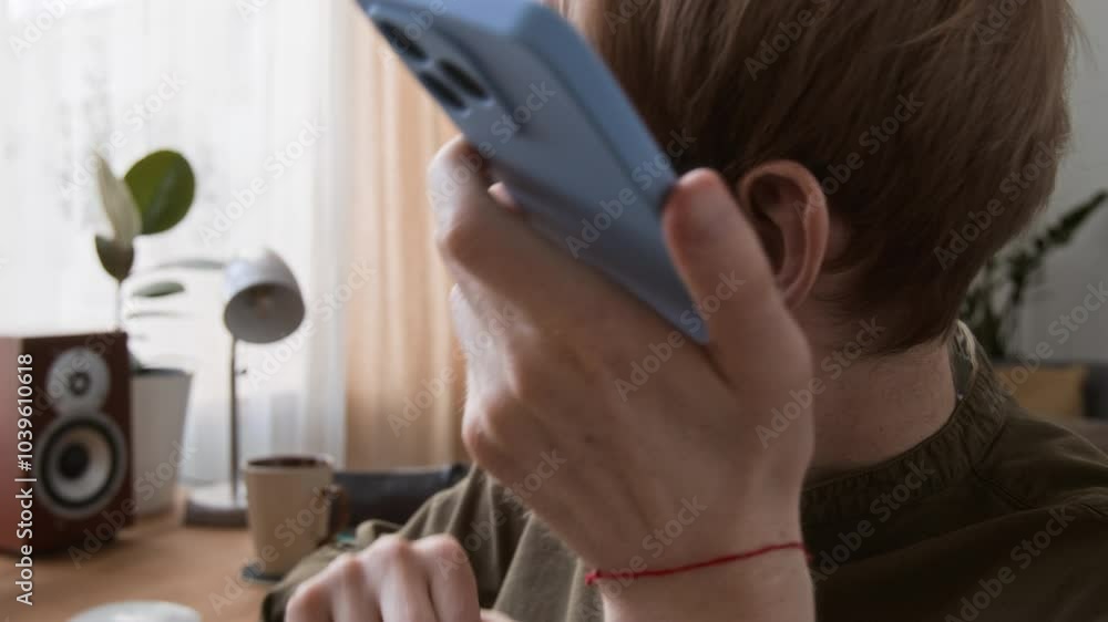 Close-up view of visually impaired man with dark glasses communicating with friend via voice messages at home Close-up view of visually impaired man with dark glasses communicating with friend via voice messages at home