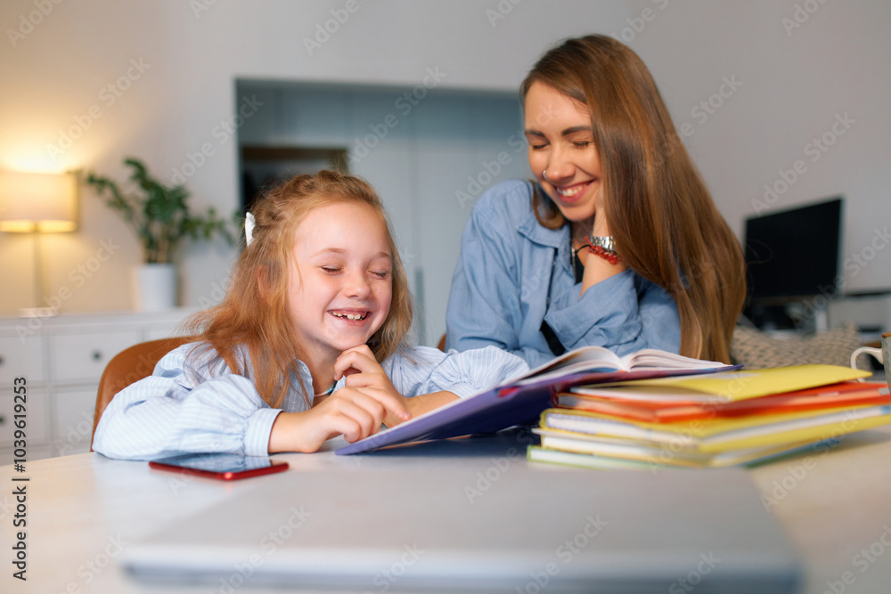 A schoolgirl sits with her mother and carefully studies the school curriculum at home A schoolgirl sits with her mother and carefully studies the school curriculum at home