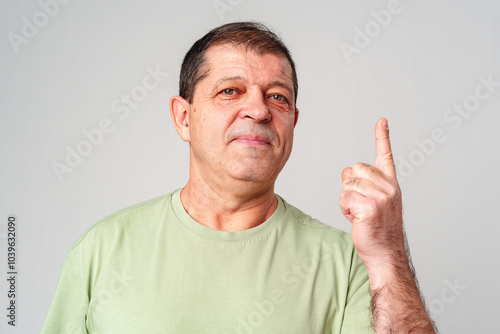 A man in a light green shirt raises his finger, signifying an important message