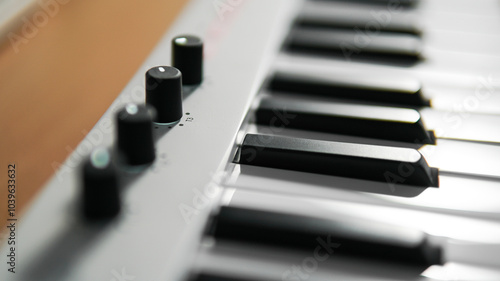 Closeups of a piano, midi controller, or keyboard with adjustable knob on a wooden table. Home studio or music equipment concept. photo