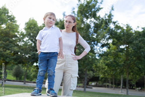 A woman and a child are standing in a park