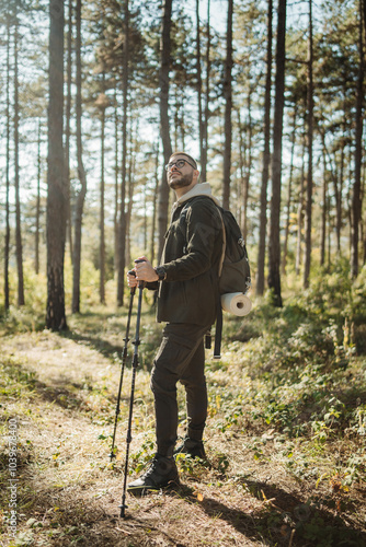 Young caucasian man hiking or trekking through the forest 