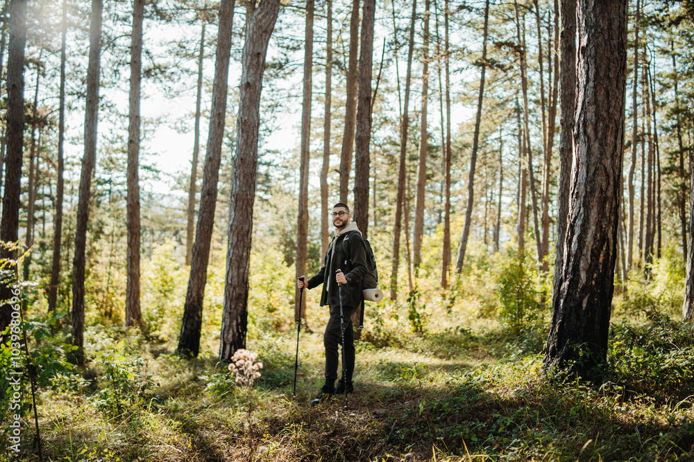 Obraz premium Young caucasian man hiking or trekking through the forest 