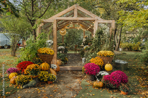 Fototapeta Naklejka Na Ścianę i Meble -  Charming garden greenhouse adorned with autumn flowers and pumpkins