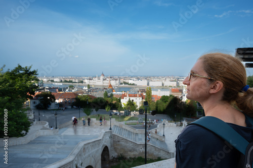 Budapest, Hungary. August 26, 2022. Aerial view of the city overlooking the Danube. A middle-aged woman gazes in fascination at the magnificent landscape. Travel destinations, travel lifestyle.