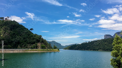 Wallpaper Mural Scenic view of a tranquil lake surrounded by lush green hills under a clear blue sky, ideal for summer vacations Torontodigital.ca