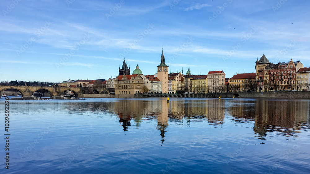 Fototapeta premium Scenic view of Prague's historic skyline and Charles Bridge reflecting on the Vltava River, evoking travel and cultural heritage