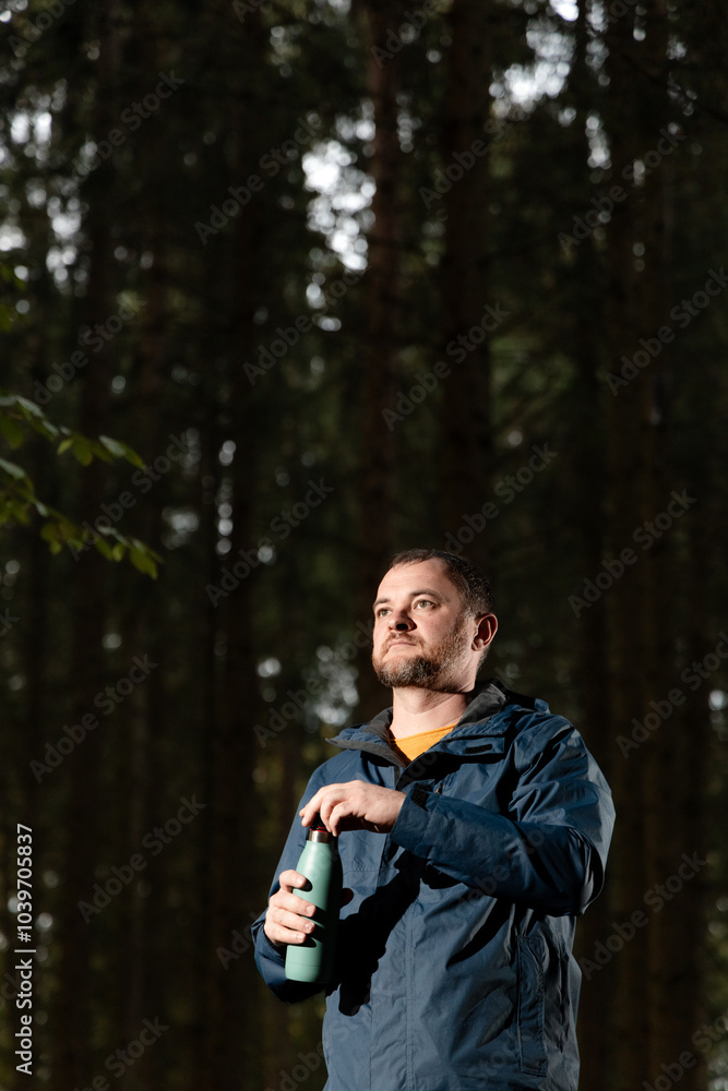 a man in the forest stopped to drink water from a thermos. drinking hot. Rest. healthy lifestyle concept. Water balance a man in the forest stopped to drink water from a thermos. drinking hot. Rest. healthy lifestyle concept. Water balance