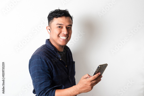 Handsome Asian man listening music using mobile phone and wireless headset photo