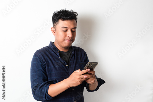 Adult Asian young man looking to his mobile phone photo