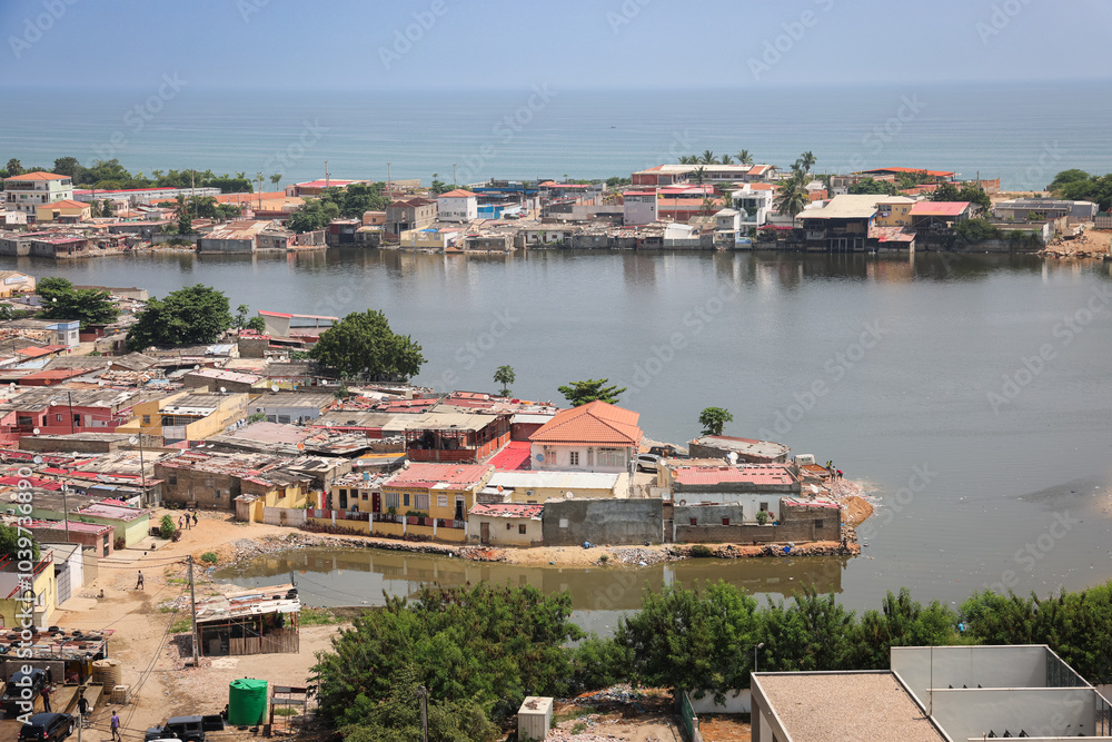 Naklejka premium View of coastal neighborhoods along the shoreline of Luanda Angola showcasing urban life beside the water and lush green areas