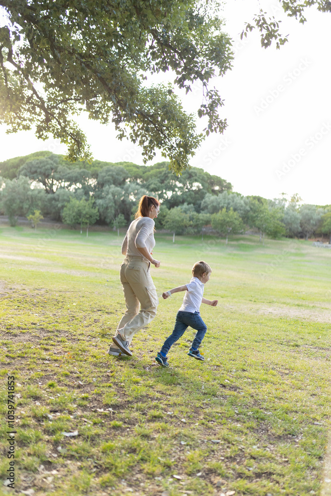 Mother and son running together through park on sunny day Mother and son running together through park on sunny day