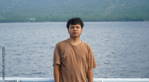 A Southeast Asian model wearing a brown dress against a sea backdrop