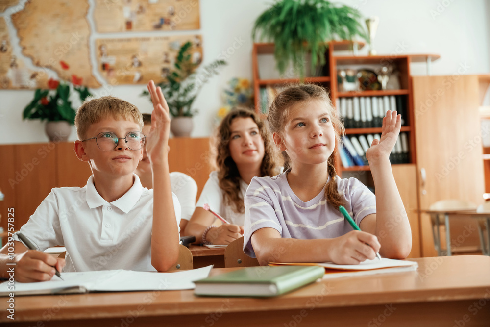 With hands up. Pupils, kids in the classroom together With hands up. Pupils, kids in the classroom together
