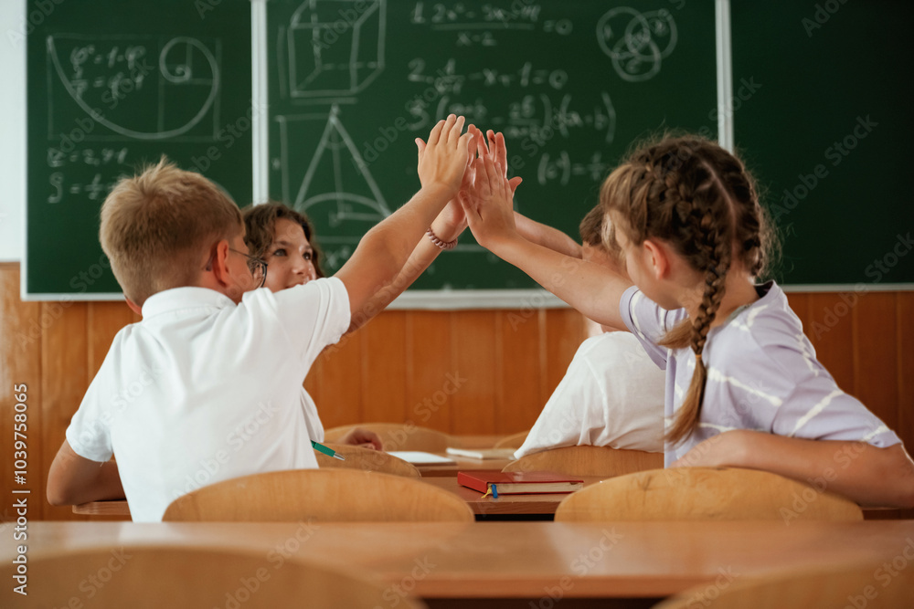 High five gesture. Pupils, kids in the classroom together High five gesture. Pupils, kids in the classroom together