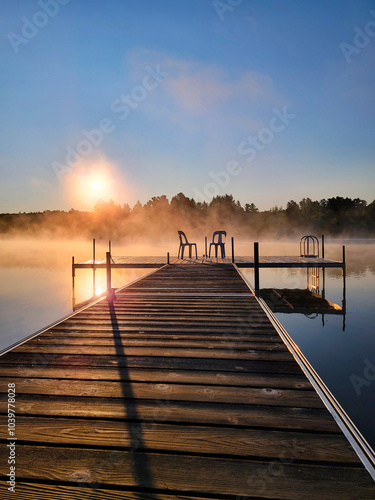 Plastic Chairs on Wooden Deck Overlooking a Misty Lake on a Calm Summer Morning