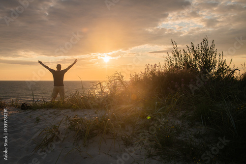 silhouette of a happy man in the sunset in the dunes near the ocean