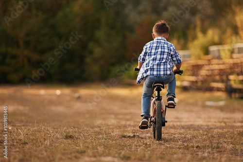 Riding, having fun. Cute boy is with his bicycle on the field