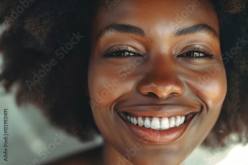 Portrait of a smiling woman with an afro, showcasing her skincare and cosmetic routine in a studio setting, expressing happiness while touching her face