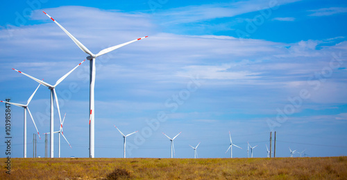 Fleet of power generators in motion. The blades of the wind farm rotate against the sky. The concept of extracting electricity from renewable sources. Wind turbine to generate electricity.