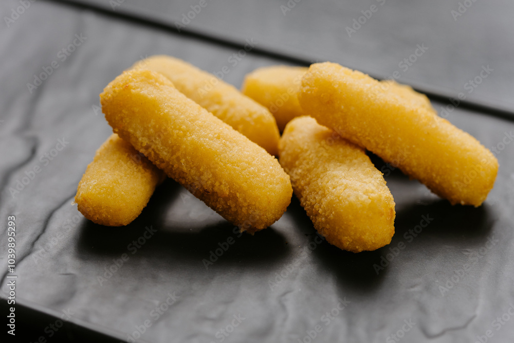 Crispy cheese sticks served on a black plate, perfect snack or appetizer for any occasion Crispy cheese sticks served on a black plate, perfect snack or appetizer for any occasion